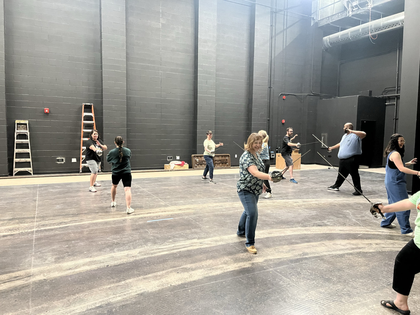 Several high school teachers learn stage combat on stage.