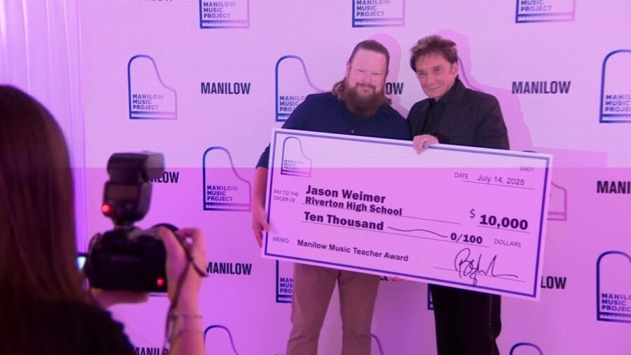 Weimer (L) and Manilow (R) stand smiling side-by-side in Manilow's presentation of a $10K grant from the Manilow fund.